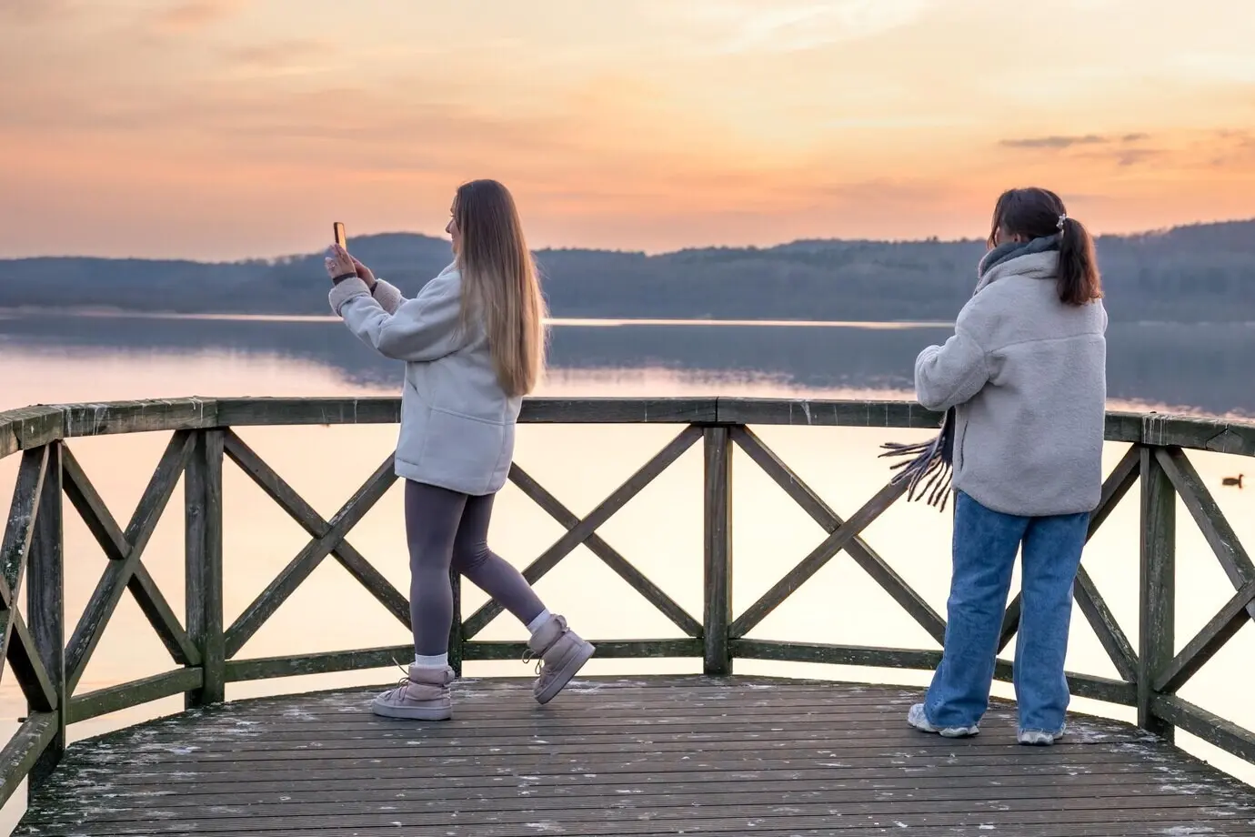 Друзья наблюдают закат на озере и гуляют на природе на закате на пирсе/пристани.